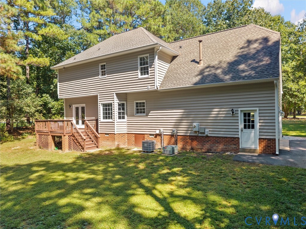 Exterior featuring beige siding, a shingled roof, a wooden deck with stairs, double glass doors, and a side entry door