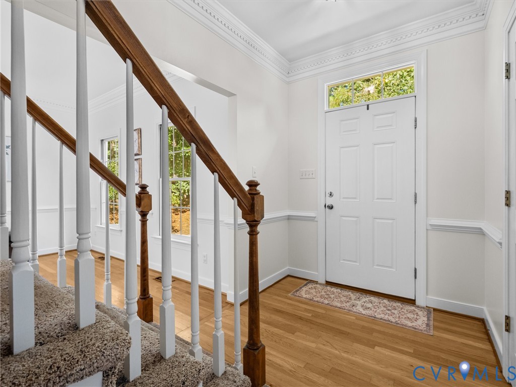 Hardwood flooring, crown molding, chair rail molding, white panel front door, and a transom window Hardwood flooring, crown molding, chair rail molding, white panel front door, and a transom window
