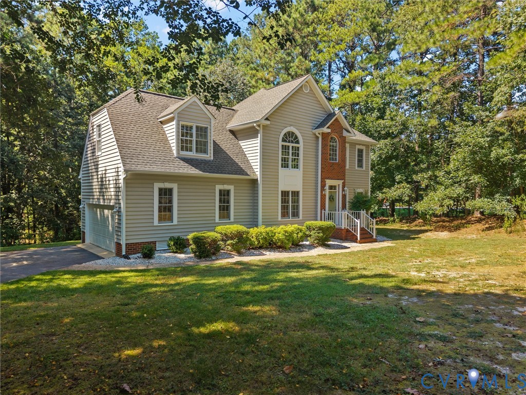 Two-story residence featuring light-colored siding and a brick facade accent