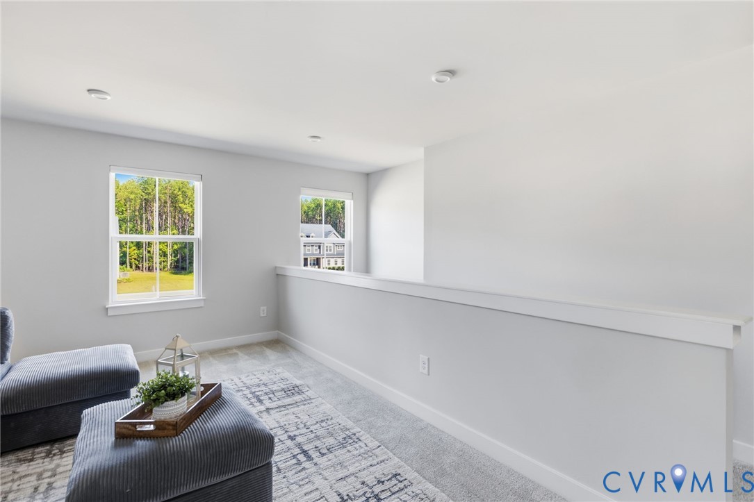 Carpeted flooring, recessed ceiling lighting, and two windows with white trim