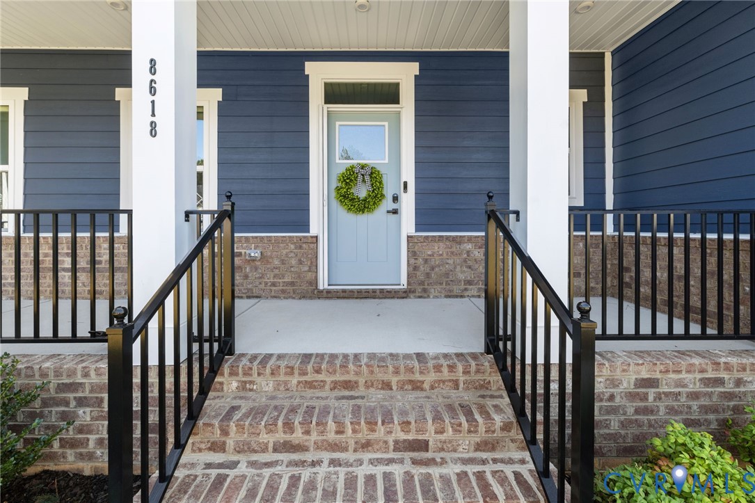 Front porch featuring brick stairs, black metal railings, and a blue siding exterior