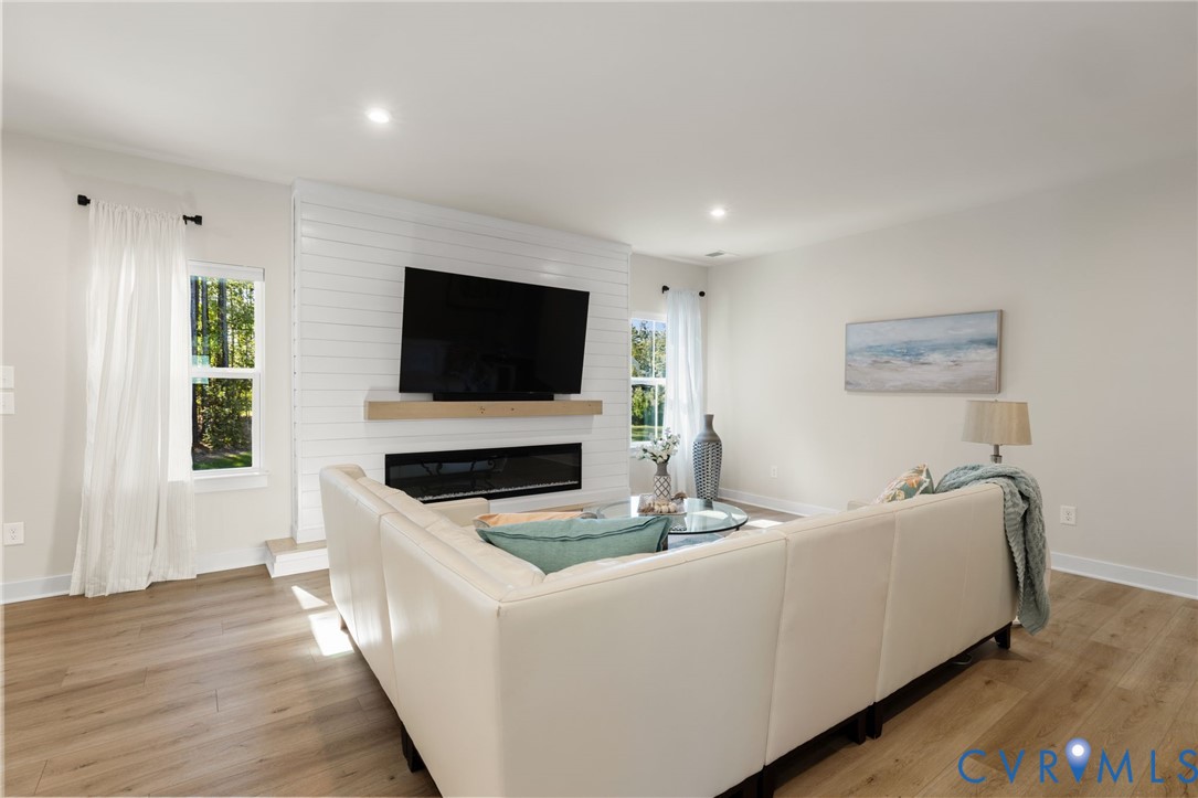 Wood-finish flooring throughout, recessed lighting, and a shiplap accent wall with a built-in electric fireplace and wood mantel