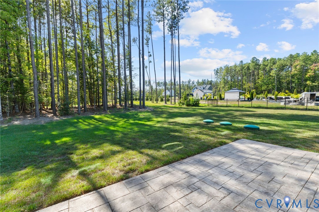 Expansive grassy yard with mature trees and a stamped concrete patio