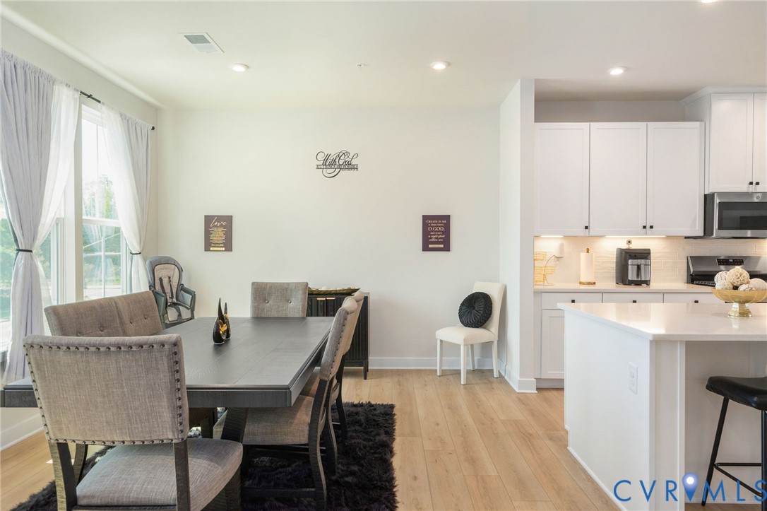 Open-concept living space featuring wood-finish flooring, recessed lighting, and large windows