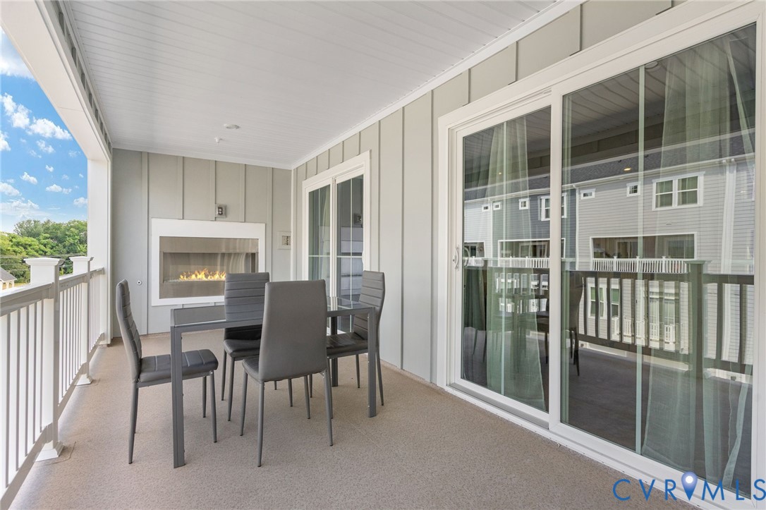 Outdoor living space featuring a built-in fireplace, sliding glass doors, white railing, and a textured floor