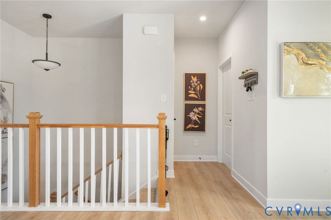Hardwood-finish flooring, white walls, and a staircase with natural wood newel posts and railings