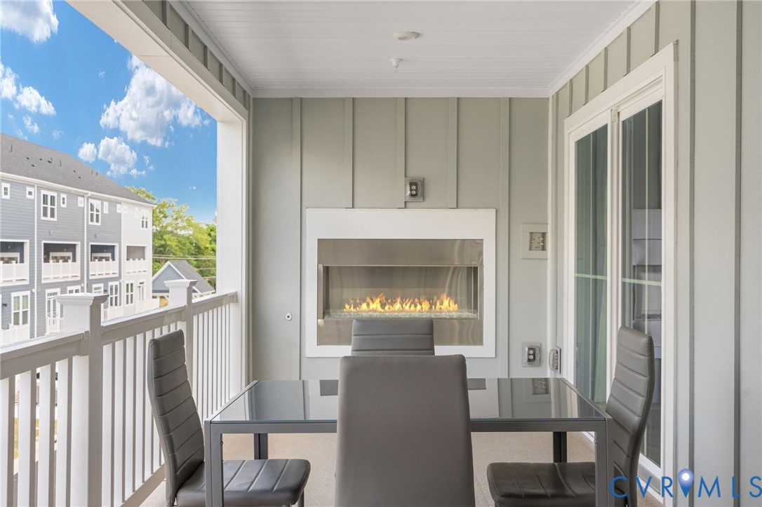 Covered balcony featuring a built-in fireplace, vertical panel wall treatment, and white railings