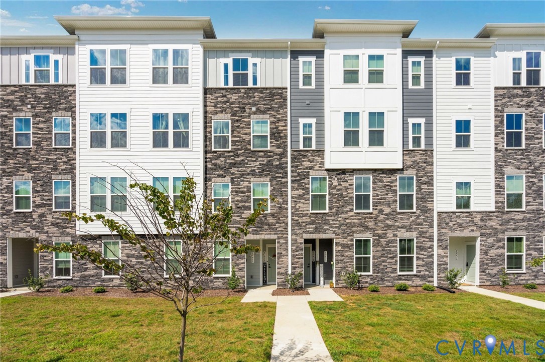 Modern multi-story facade featuring stone veneer and white siding