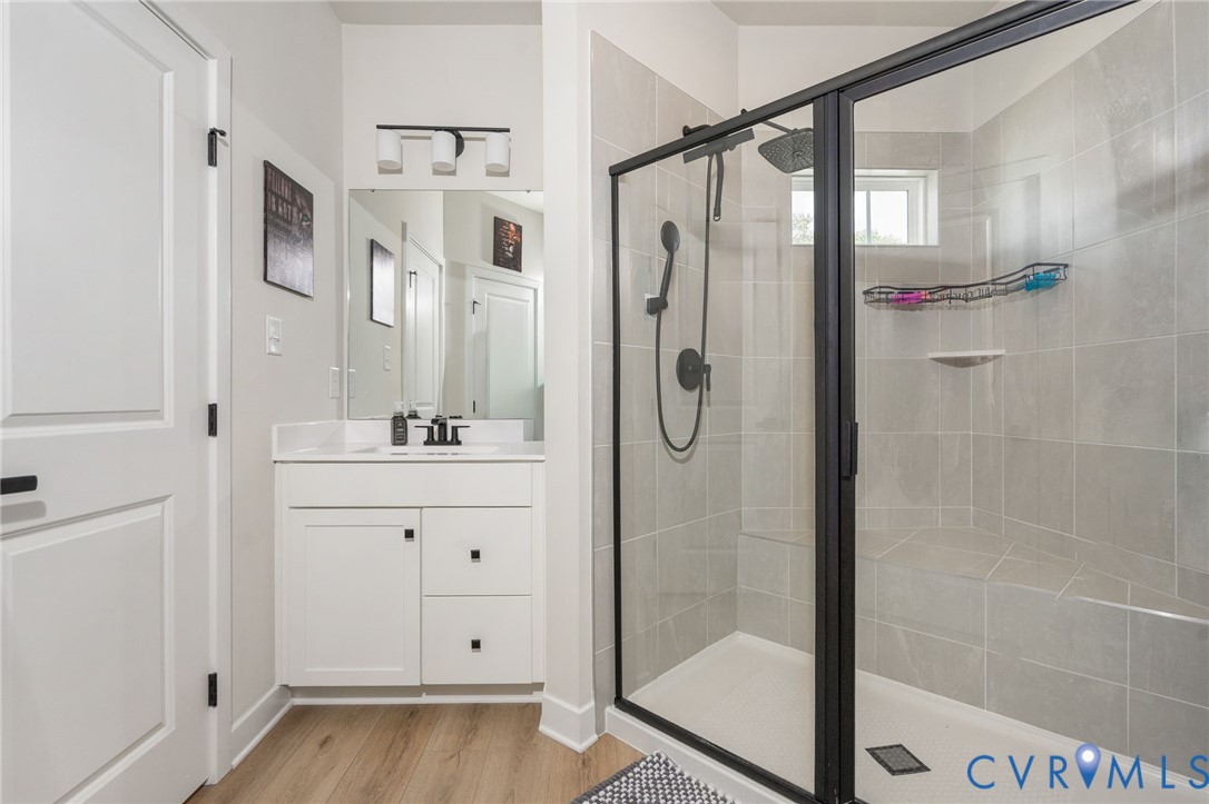 Walk-in shower with clear glass enclosure and matte black hardware, tiled walls, built-in bench, and rain shower head
