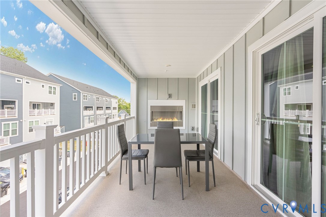 Covered balcony featuring a built-in linear fireplace, durable railing, and sliding glass doors