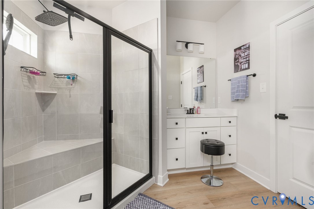 Glass-enclosed shower with tiled bench seating, rain showerhead, and transom window