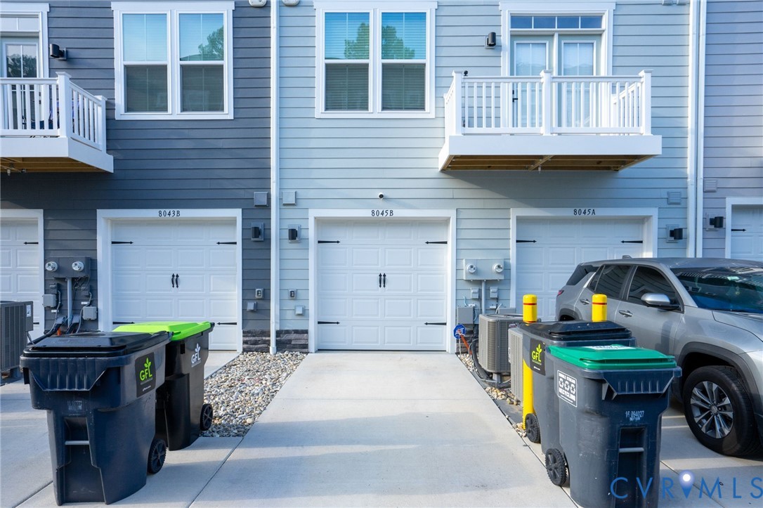 Exterior featuring horizontal siding, white-trimmed windows, and white garage doors with decorative hardware