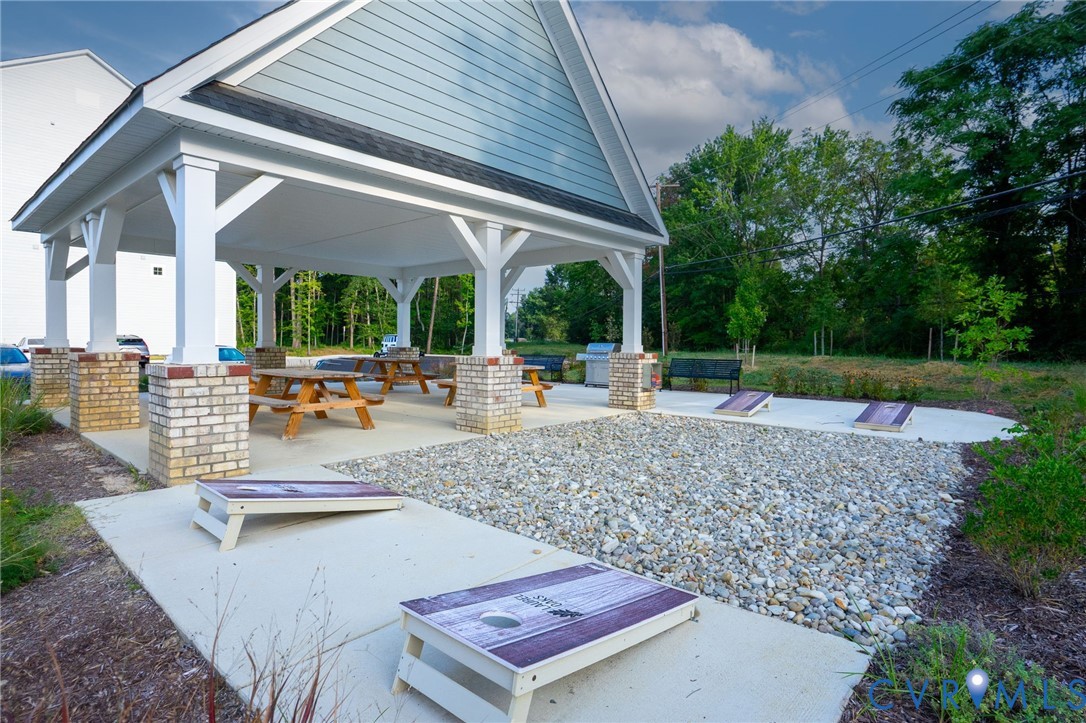 Outdoor pavilion with brick and column supports, featuring a concrete pad and gravel area