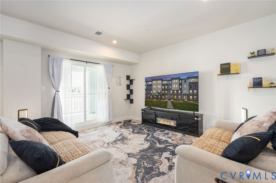 Recessed lighting, sliding glass door, white walls, and a built-in media console with an electric fireplace