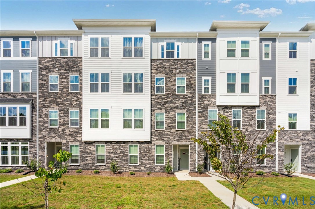 Multi-level exterior featuring stone and siding finishes, multiple windows, and a paved walkway