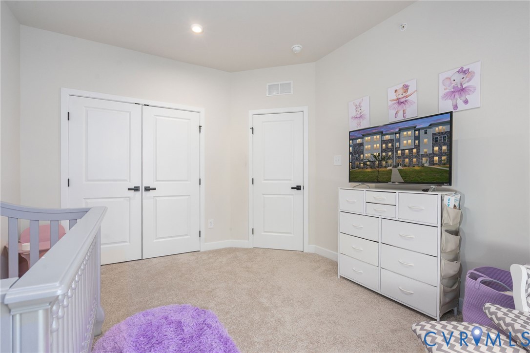 Recessed ceiling lighting, light-toned carpeting, white walls, and a white two-panel double door