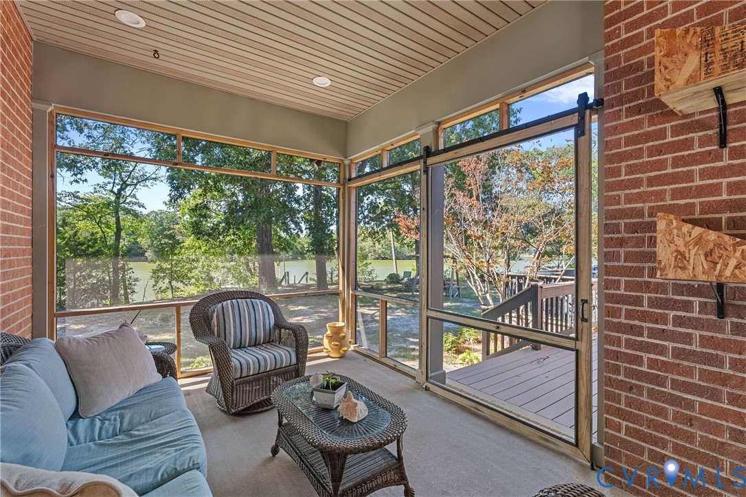 Screened porch with brick wall, wood-finish ceiling, recessed lighting, and sliding screen door