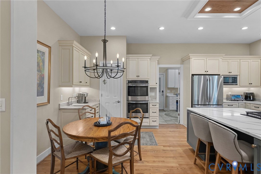 Kitchen featuring wood-finish flooring, white cabinetry, stainless steel appliances, and a central island with a light-toned countertop