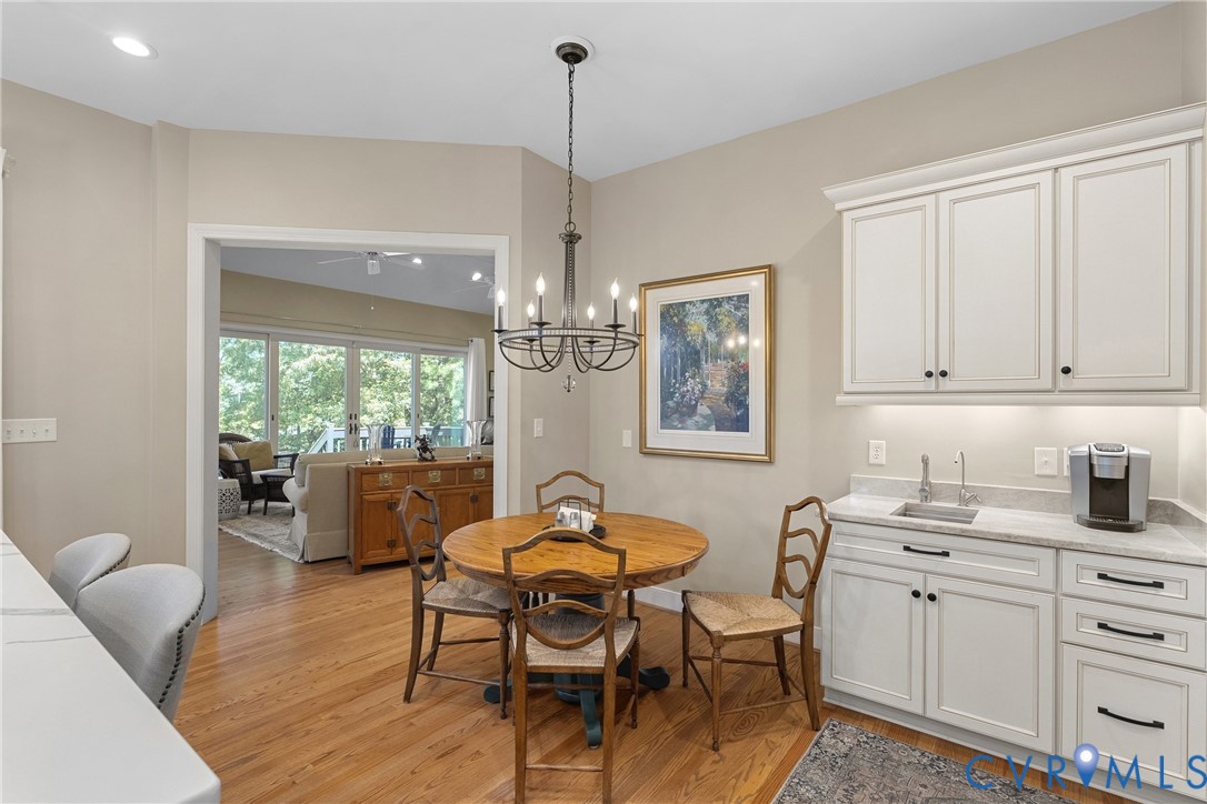 Hardwood flooring throughout, white cabinetry with dark hardware, built-in wet bar with undermount sink, and recessed lighting
