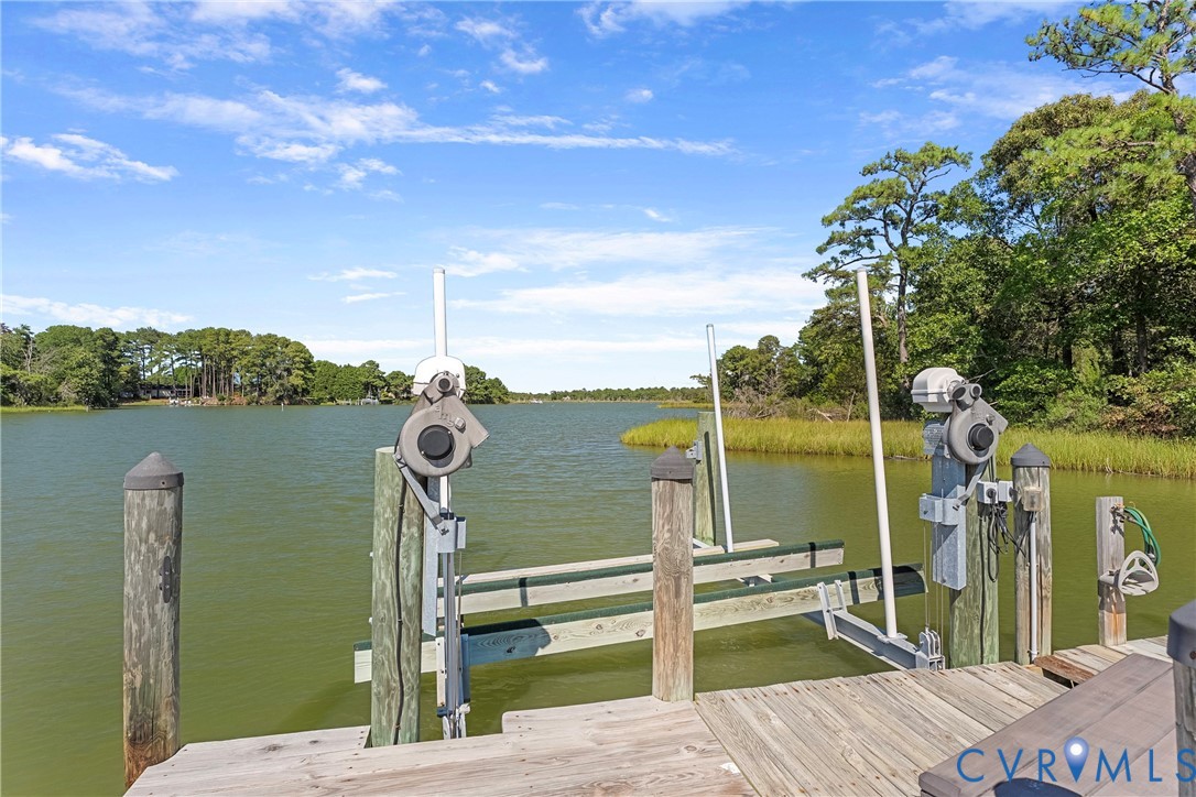 Private dock with a boat lift, featuring wooden decking and pilings, set against a natural shoreline