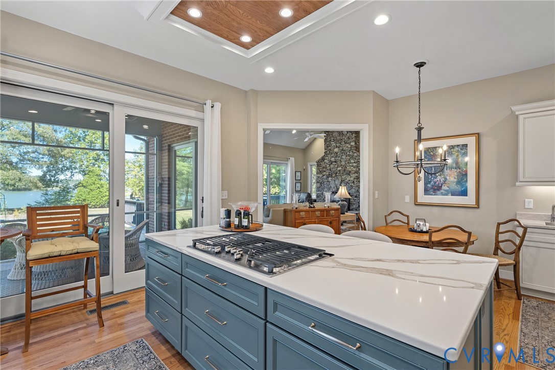 Kitchen featuring a central island with a cooktop, stone countertop, and custom blue cabinetry