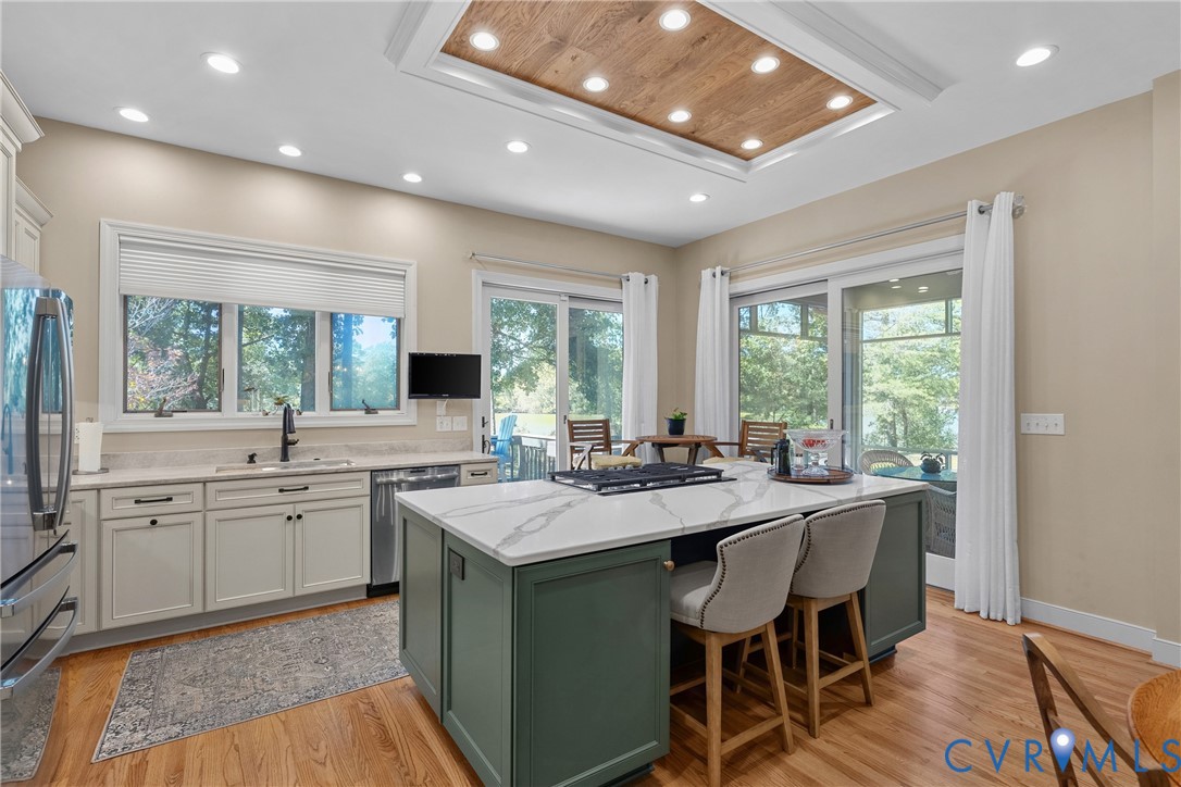 Kitchen featuring a central island with a cooktop, stone countertops, recessed lighting, wood-finish flooring, and sliding glass doors
