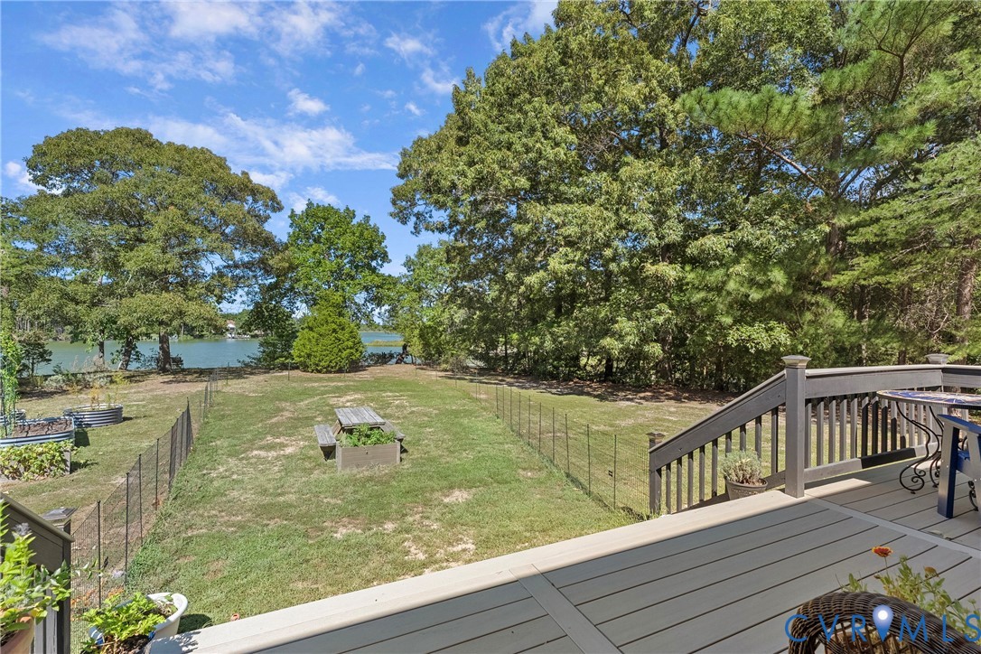 Expansive backyard with a manicured lawn, mature trees, and a body of water in the background