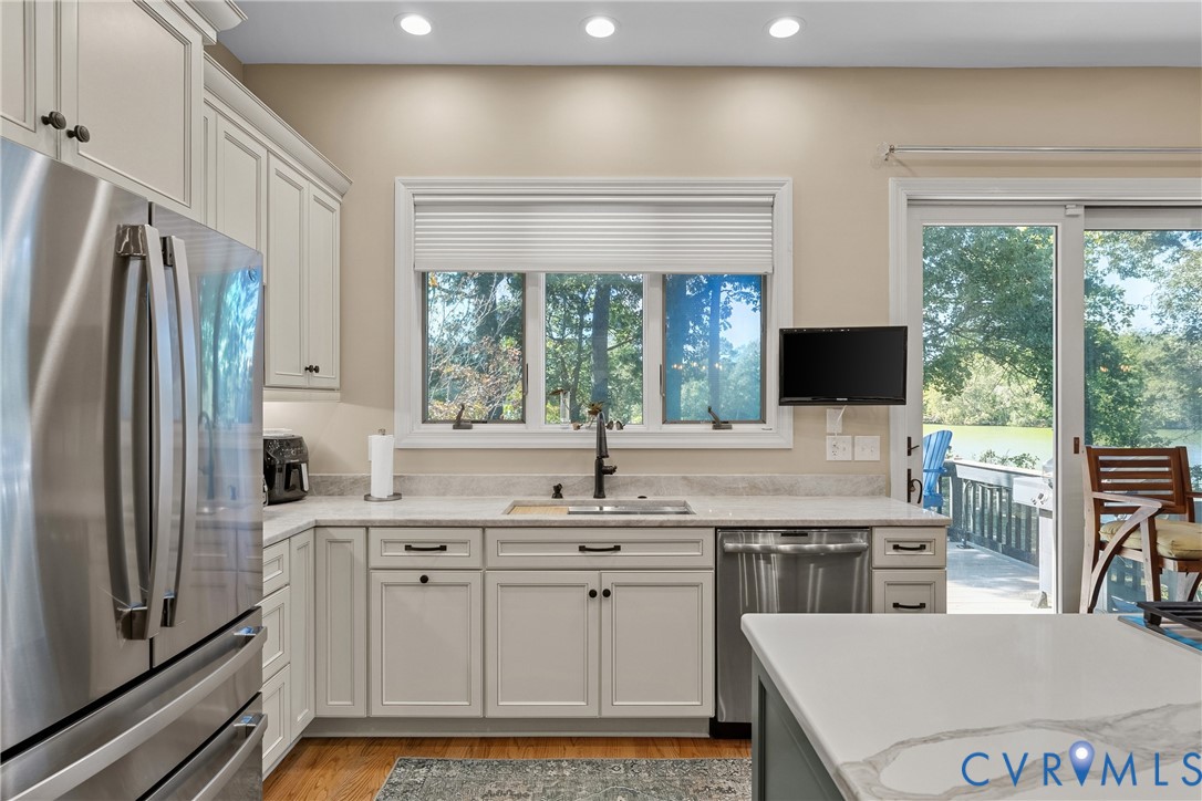 Kitchen featuring light-toned cabinetry, stainless steel appliances, recessed lighting, a built-in sink, and granite countertops