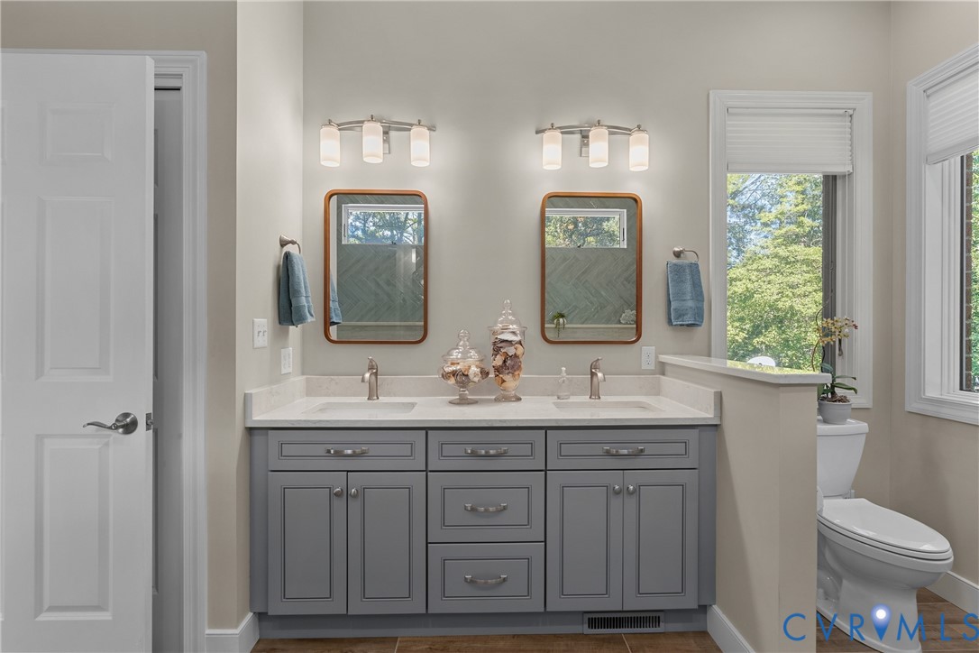 Double vanity with gray cabinetry, white countertops, and dual wall-mounted light fixtures
