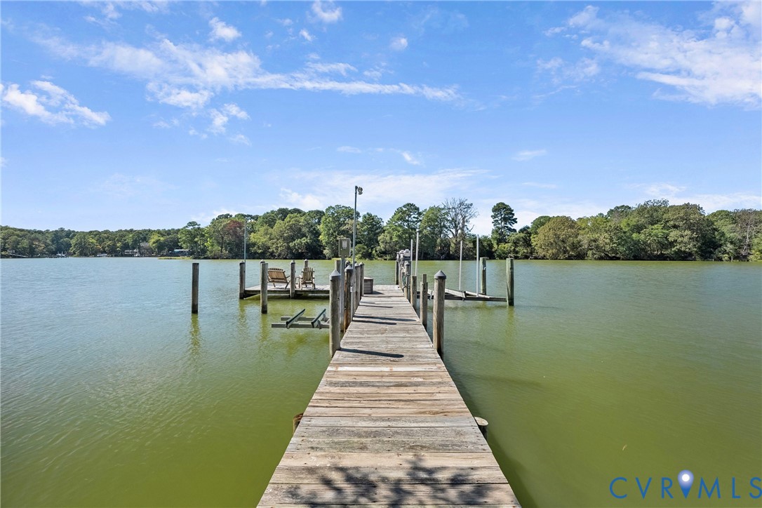 Private dock with wood planking and multiple pilings, featuring an integrated boat lift and clear water access