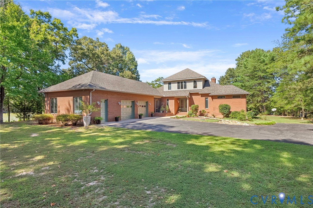 Brick exterior with a multi-level design, attached three-car garage, and a paved driveway