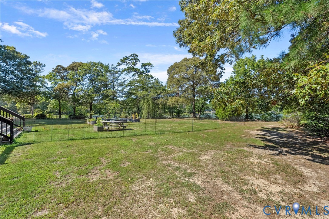 Expansive grassy property with mature trees, raised garden beds, and a wood-finish staircase