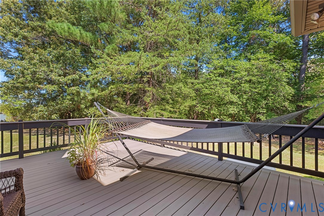 Expansive outdoor deck featuring composite decking, dark wood railing, and surrounding mature trees