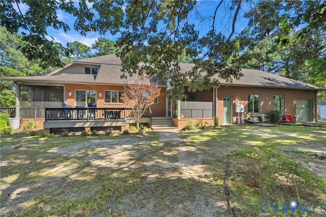 Brick exterior with multiple windows, a screened porch, and an attached wood deck