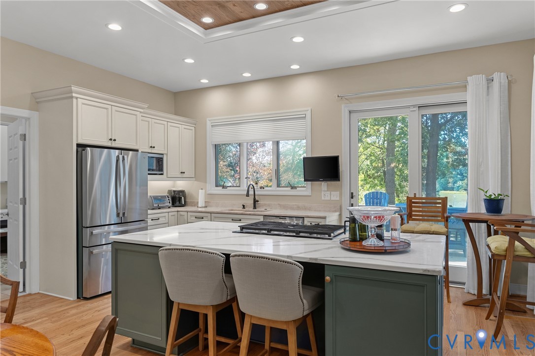 Kitchen featuring stainless steel appliances, white cabinetry, a center island with a white countertop, recessed lighting, and wood-finish flooring
