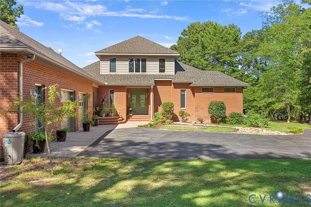 Brick exterior with an asphalt driveway, concrete walkway, and attached two-car garage