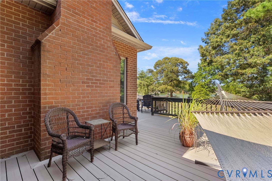 Expansive outdoor deck featuring composite decking, a brick exterior wall, and surrounding mature trees
