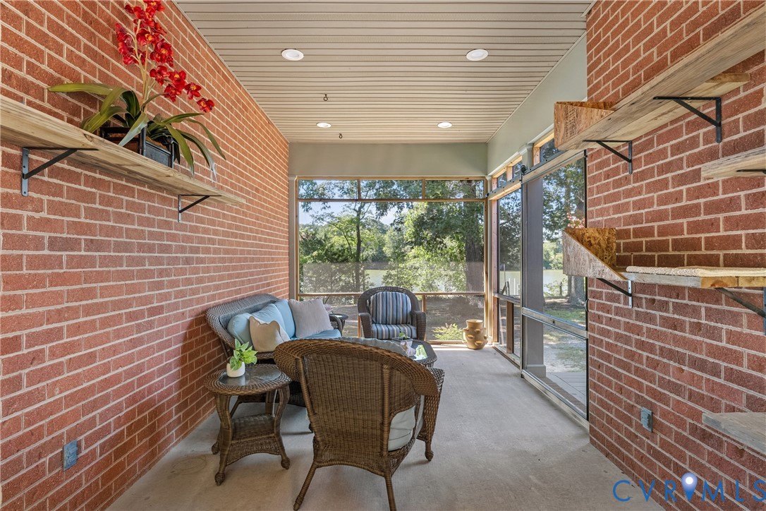 Screened porch featuring brick walls, recessed lighting, and built-in shelving