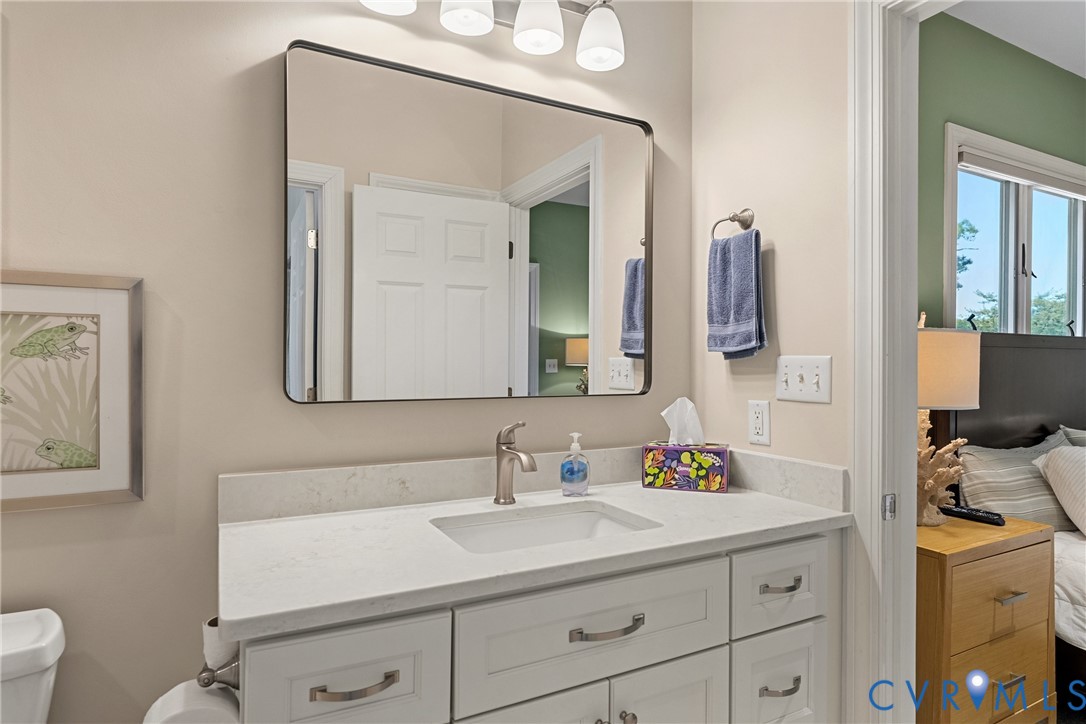 Vanity with integrated sink, brushed nickel faucet, and a rectangular mirror with a black frame