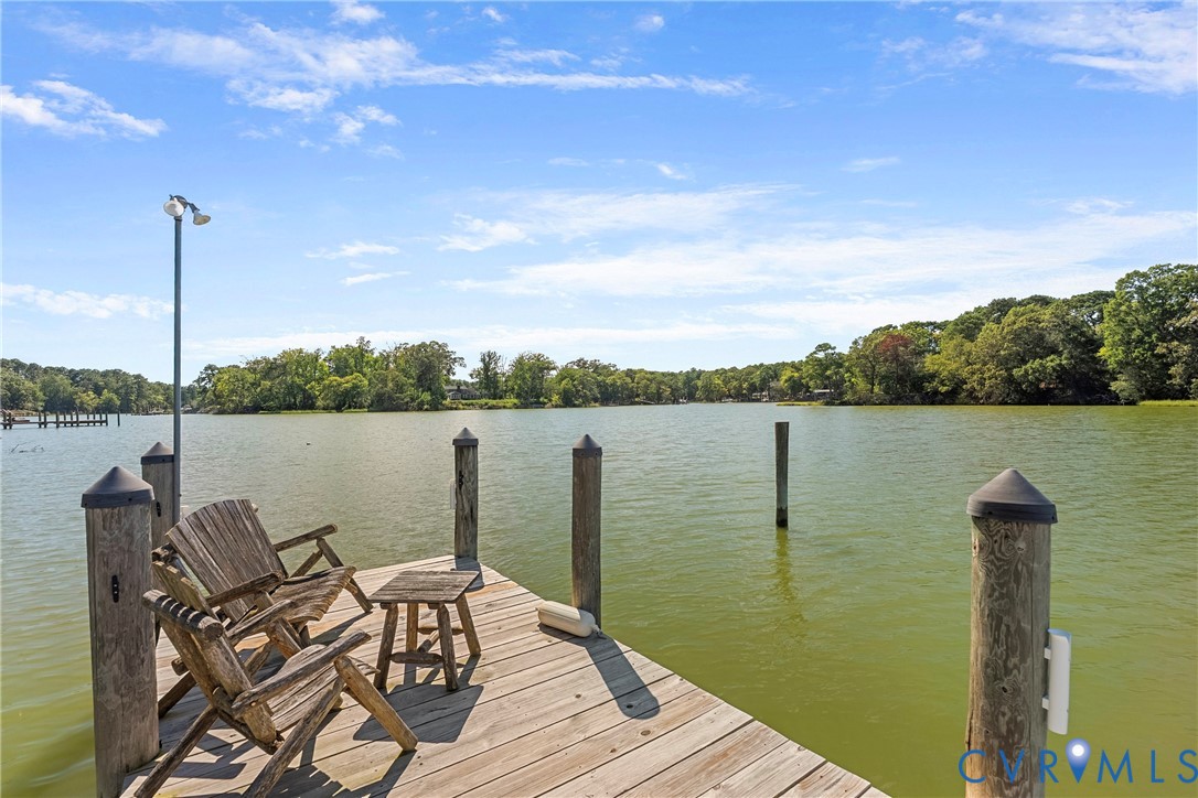 Waterfront property featuring a wood-plank dock, piling posts, and a dual-head dock light