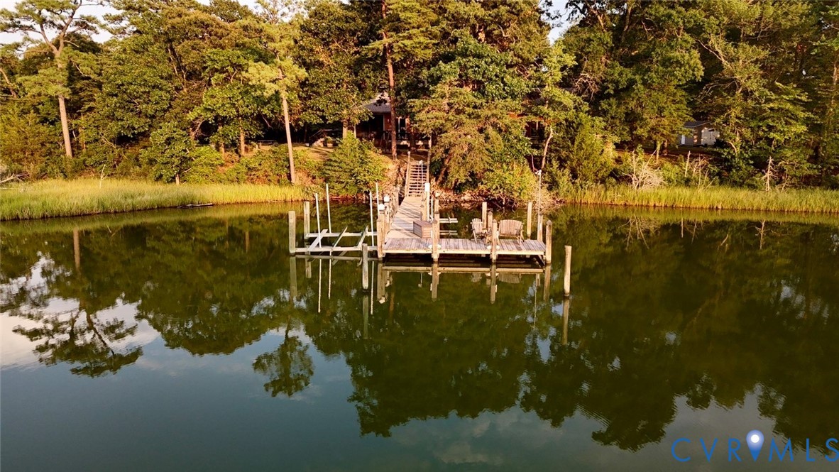 Waterside property featuring a private boat dock, lush treeline, and a tranquil body of water