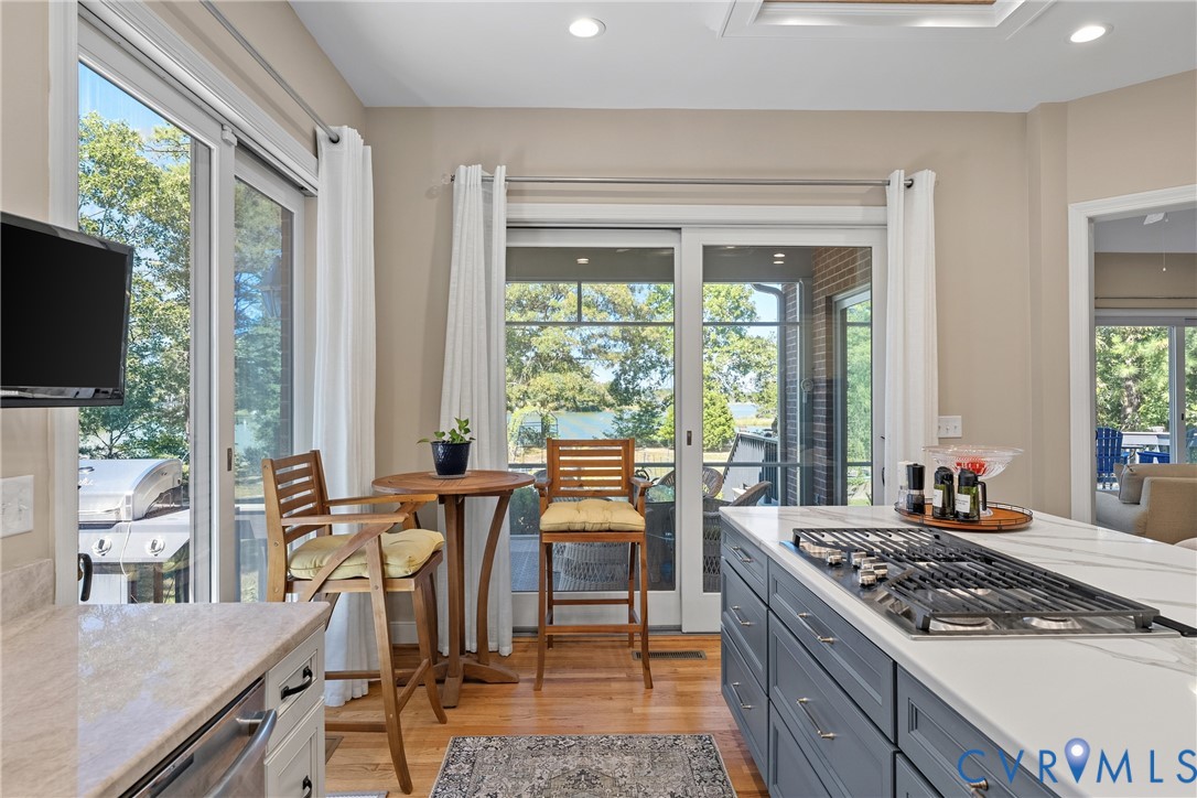 Gourmet kitchen with a built-in gas range, large center island with a stone countertop, and wood-finish flooring