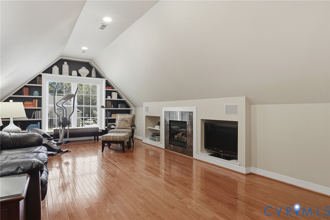 Hardwood flooring, recessed lighting, built-in shelving, integrated fireplace, and a large window