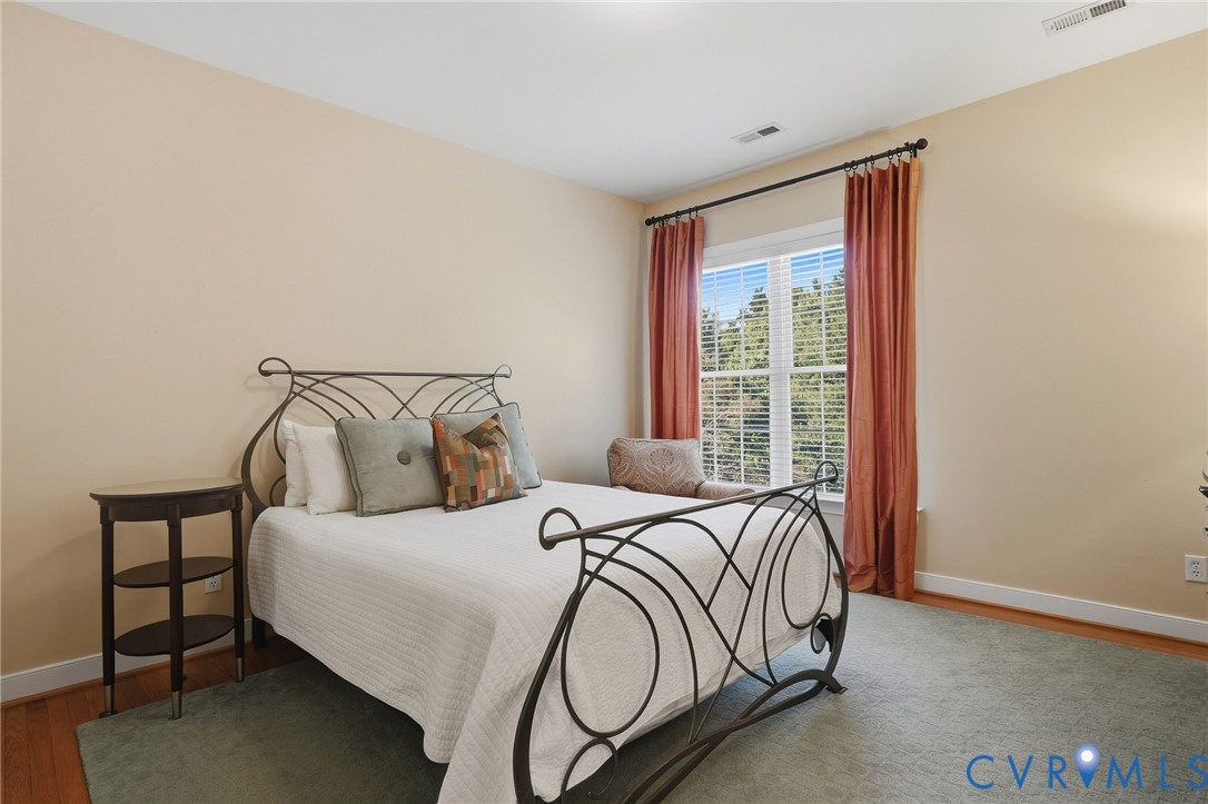 Hardwood flooring with an area rug, a large window with blinds, and neutral wall tones
