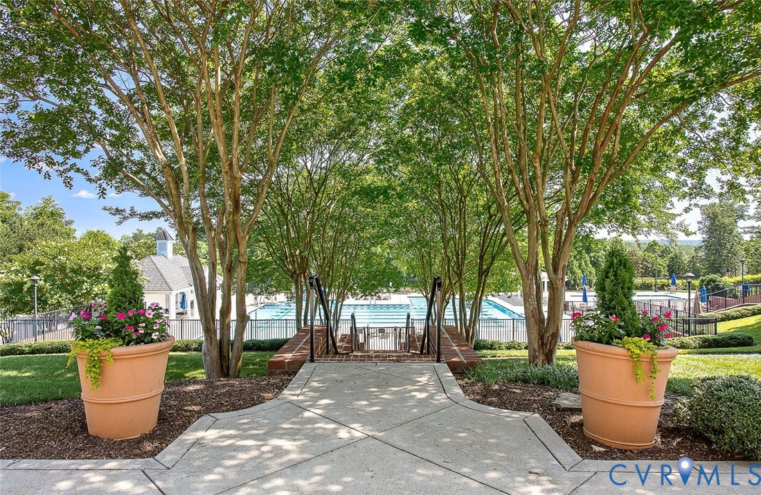 Concrete pathway leading to a fenced pool area with a building