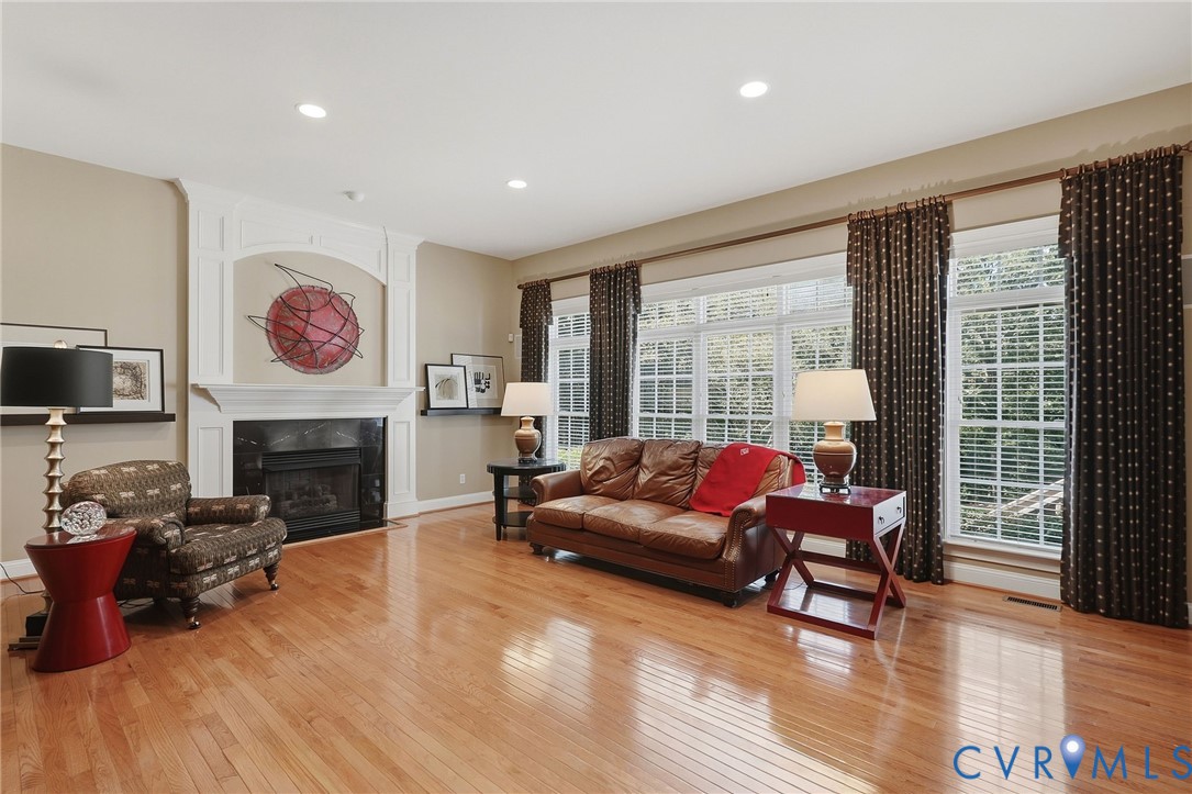 Spacious room featuring wood-finish flooring, recessed lighting, and a fireplace with an ornate white mantel