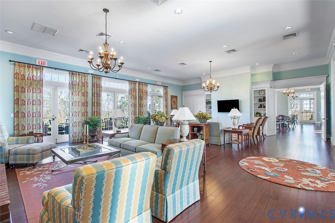 Hardwood-finish flooring, multiple sets of French doors, recessed lighting, built-in shelving, and decorative chandeliers