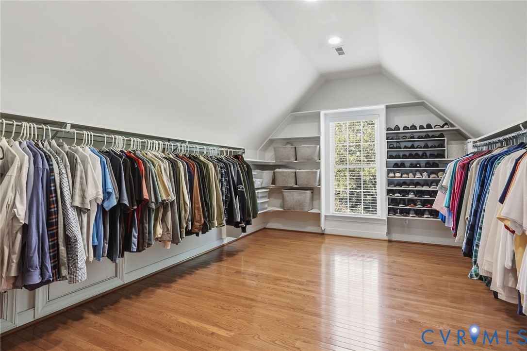 Hardwood-finish flooring with sloped ceilings, built-in shelving, and a large window