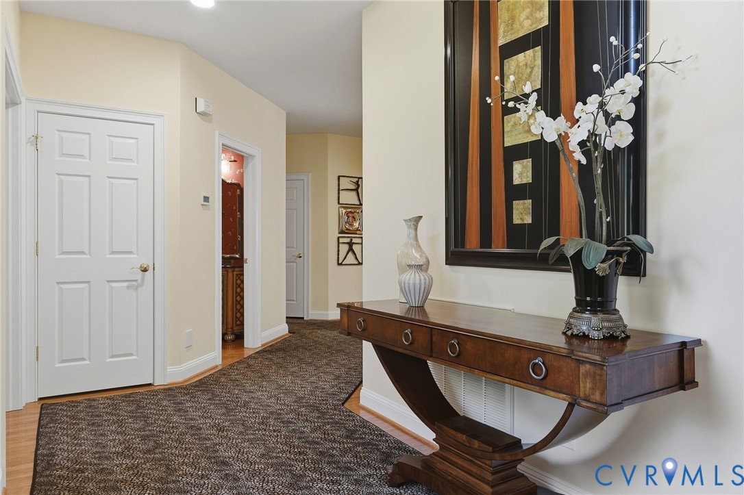 Hallway featuring a decorative console table, recessed lighting, white paneled doors, and wood-finish flooring with a patterned runner Hallway featuring a decorative console table, recessed lighting, white paneled doors, and wood-finish flooring with a patterned runner