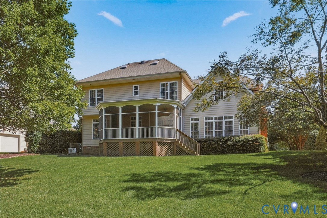 Expansive green lawn with a screened-in porch, multi-pane windows, and light-colored siding